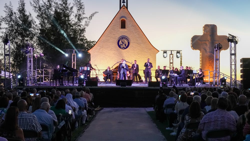 Caribbean Tenors con orquesta al atardecer frente a la capilla del Santuario de Schoenstatt, con el público de pie