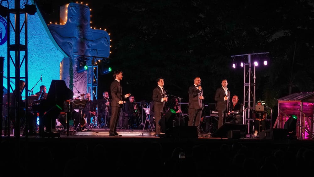 Los cuatro tenores cantan de noche con la orquesta y la cruz iluminada del Santuario de Schoenstatt detrás